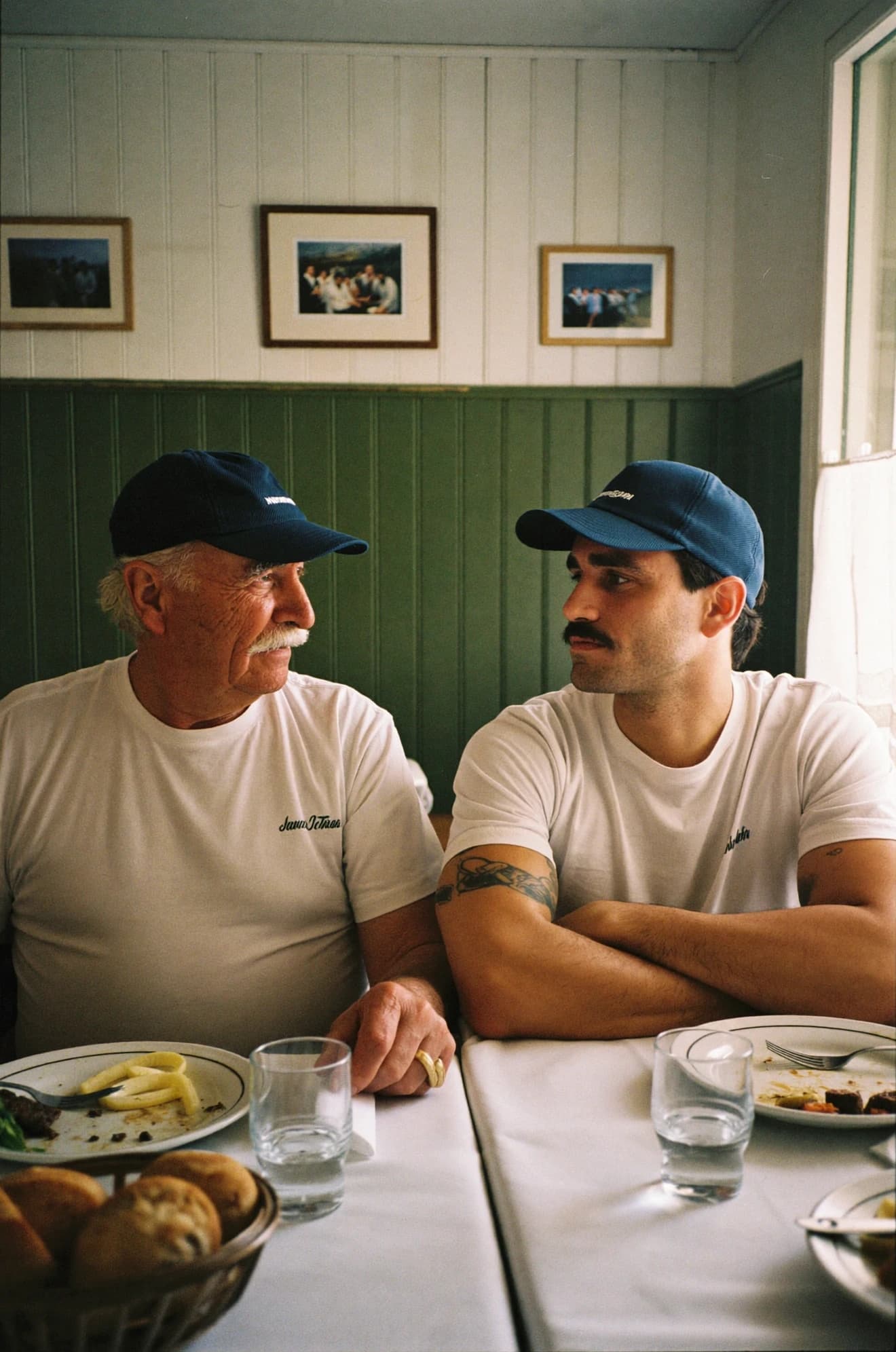 Two hospitality workers, one older and one younger, talking over a meal.